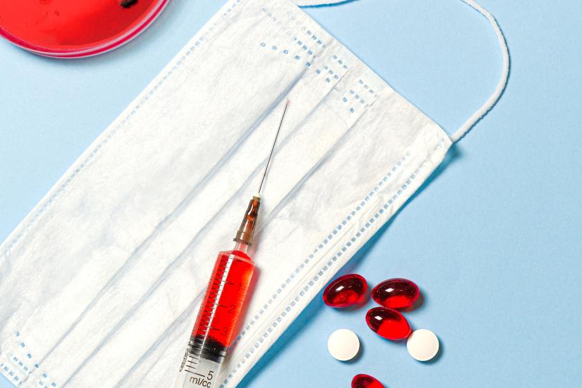 petri dish, syringe, mask, and pills on blue table